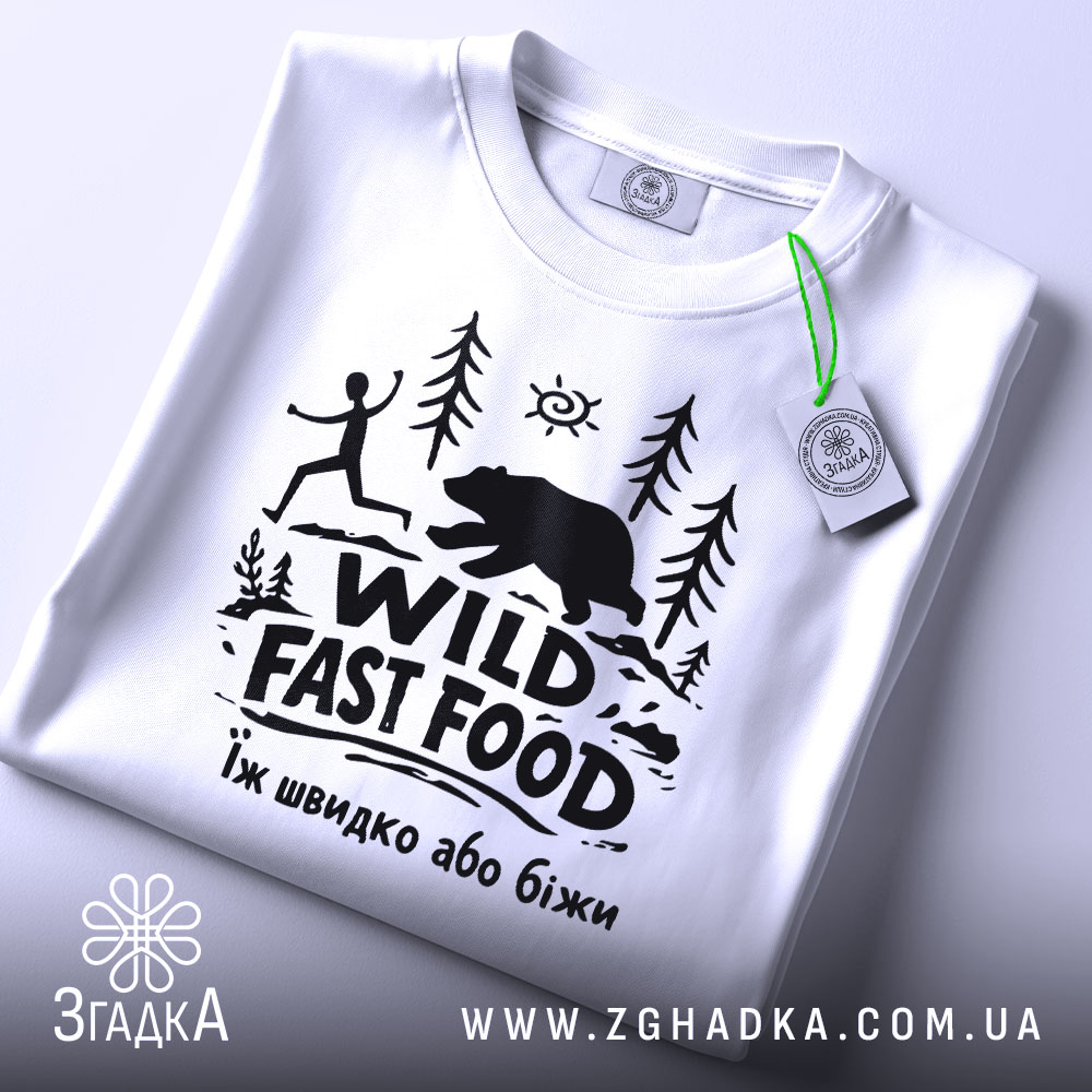 Футболка Wild Fast Food білого кольору, складена на поверхні, з видимим етикеткою, фон світлий, принт чорного кольору з малюнком людини, що біжить, та ведмедя на фоні лісу.