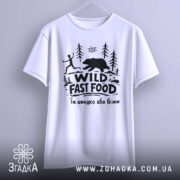Футболка Wild Fast Food білого кольору, підвішена на вішалці, фон світлий, принт чорного кольору з малюнком людини, що біжить, та ведмедя на фоні лісу.