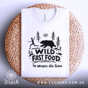 Футболка Wild Fast Food білого кольору, складена на плетеній основі, фон світлий, принт чорного кольору з малюнком людини, що біжить, та ведмедя на фоні лісу.
