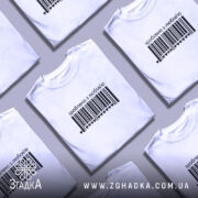 Футболка зроблено з любов’ю, біла, на моделі, з чорним принтом у вигляді штрих-коду та написом 'зроблено з любов’ю', фон світло-фіолетовий, модель з легким макіяжем та розпущеним волоссям.