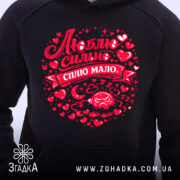 Худі Люблю коли злиш чорного кольору, з капюшоном, з близького ракурсу, на фоні світлого, з яскравим червоним принтом, що містить напис "Люблю сильно, сплю мало" та елементи декору у формі сердечок.