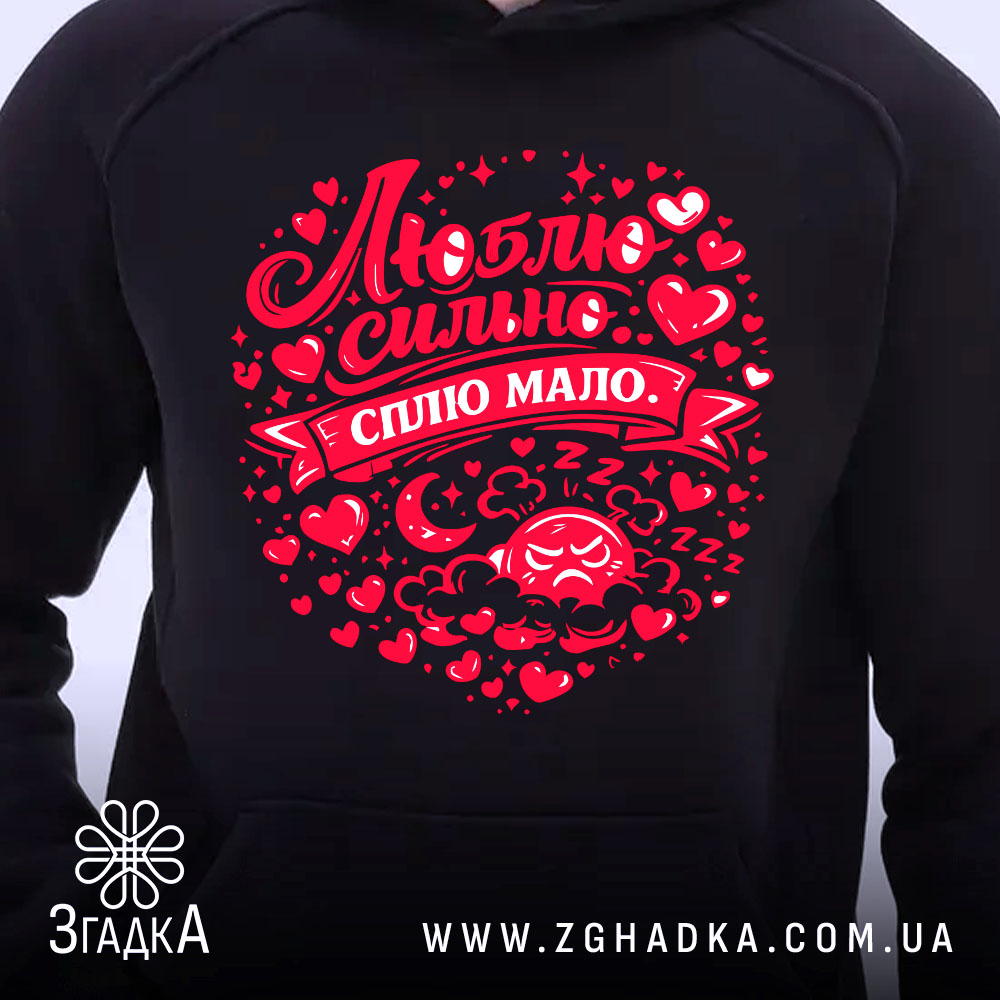 Худі Люблю коли злиш чорного кольору, з капюшоном, з близького ракурсу, на фоні світлого, з яскравим червоним принтом, що містить напис "Люблю сильно, сплю мало" та елементи декору у формі сердечок.