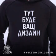 Худі з вашим дизайном, темно-синього кольору, з ракурсу спереду, на фоні світлий, великий принт з написом "ТУТ БУДЕ ВАШ ДИЗАЙН", капюшон, видно частину кишені-«кенгуру», манжети з еластичної тканини.