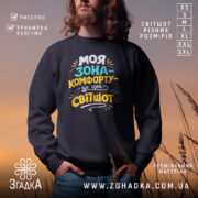 Світшот моя зона комфорту, чорного кольору, з круглою горловиною, на моделі з бородою, фон з м'яким градієнтом, принт з написом яскравих кольорів, манжети та трикотажна резинка на поясі, фактура м'яка та приємна на дотик.