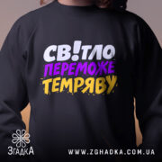 Світшот світло переможе темряву — світшот, крупний план принта на нейтральному фоні.