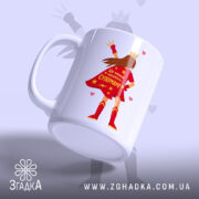 Чашка для Супермами, біла, зображена з легким нахилом, на фоні світло-фіолетового кольору, з принтом супергероїні в червоному плащі, на якому написано 'Ця чашка належить Супермамі', ручка класична, край рівний, глянцевий.