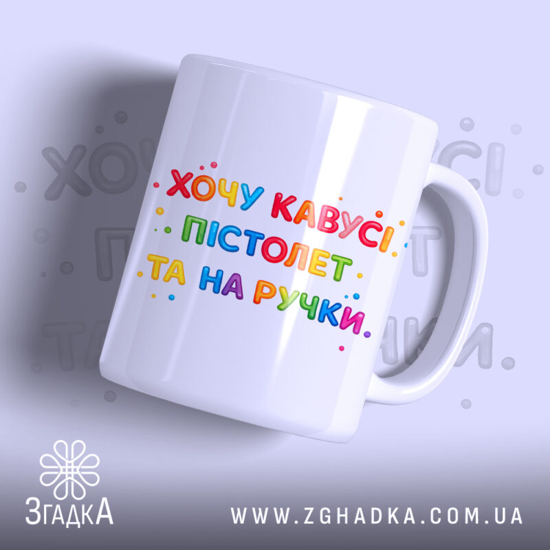 Чашка прикол хочу кавусі. Чашка білого кольору з яскравим принтом, на якому написано 'Хочу кавусі, пістолет та на ручці'. Принт виконаний у різнокольорових літерах, фон світло-сірий. Ручка чашки гладка, край рівний, поверхня глянцева.