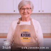 Фартух Бабуся на кухні, бежевого кольору, зображений на манекені з ракурсу спереду, фон світлий, принт з текстом 'У Бабусі на кухні завжди смачно' виконаний в темно-синьому та жовтому кольорах.