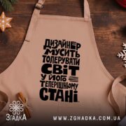 Фартух дизайнер толерує світ, бежевий, на дерев'яному фоні, бренд Згадка.