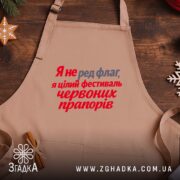 Фартух фестиваль червоних прапорів, бежевий, на дерев'яному фоні, текст яскравий, бренд Згадка.