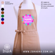 Фартух головна мама країни, бежевого кольору, зображений на манекені, фон нейтральний, принт з яскравими квітами та написом 'Головна мама країни'.