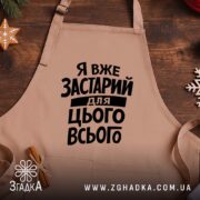 Фартух я вже застарий для цього всього, бежевий, на дерев'яному фоні, бренд.