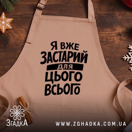 Фартух я вже застарий для цього всього, бежевий, на дерев'яному фоні, бренд.