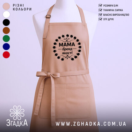 Фартух Мама бежевого кольору, зображений з переднього ракурсу на манекені, фон однотонний світлий, принт чорного кольору з написом 'Мама бренд якості' в оточенні листя.