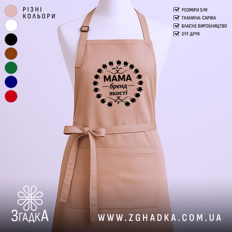 Фартух Мама бежевого кольору, зображений з переднього ракурсу на манекені, фон однотонний світлий, принт чорного кольору з написом 'Мама бренд якості' в оточенні листя.