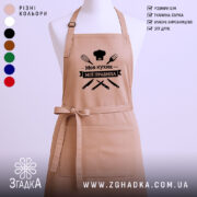 Фартух моя кухня мої правила. Фартух бежевого кольору, зображений з фронтального ракурсу на манекені. Фон світлий, з простим дизайном. Принт чорного кольору з написом 'Моя кухня мої правила' та зображеннями кухонних інструментів.