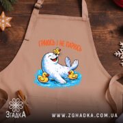 Фартух морський котик і качечки, бежевий фон, на дерев'яному столі, бренд Згадка.