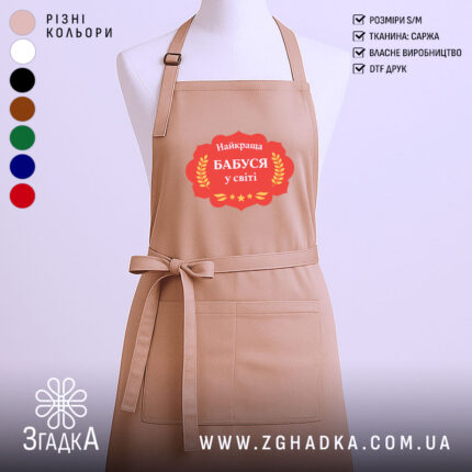 Фартух найкраща бабуся, бежевого кольору, зображений на манекені, фон однотонний, принт з написом 'Найкраща Бабуся у світі' в червоній рамці з зірками.