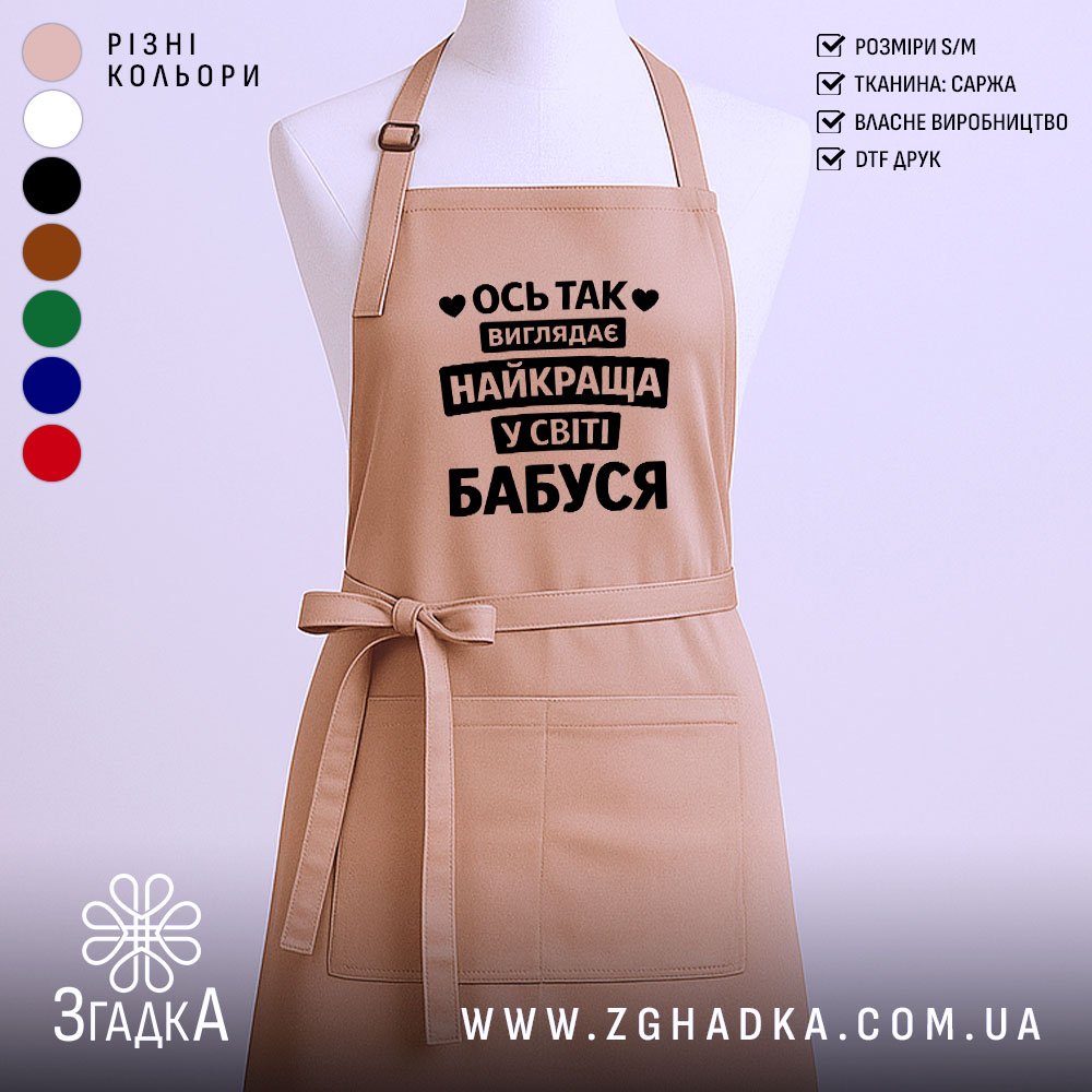 Fartukh Naikrashcha Babusia U Sviti Hordist Kukhni 1 Фартух найкраща бабуся, бежевого кольору, зображений на манекені, фон світлий, принт чорного кольору з текстом 'Ось так виглядає найкраща у світі бабуся'.
