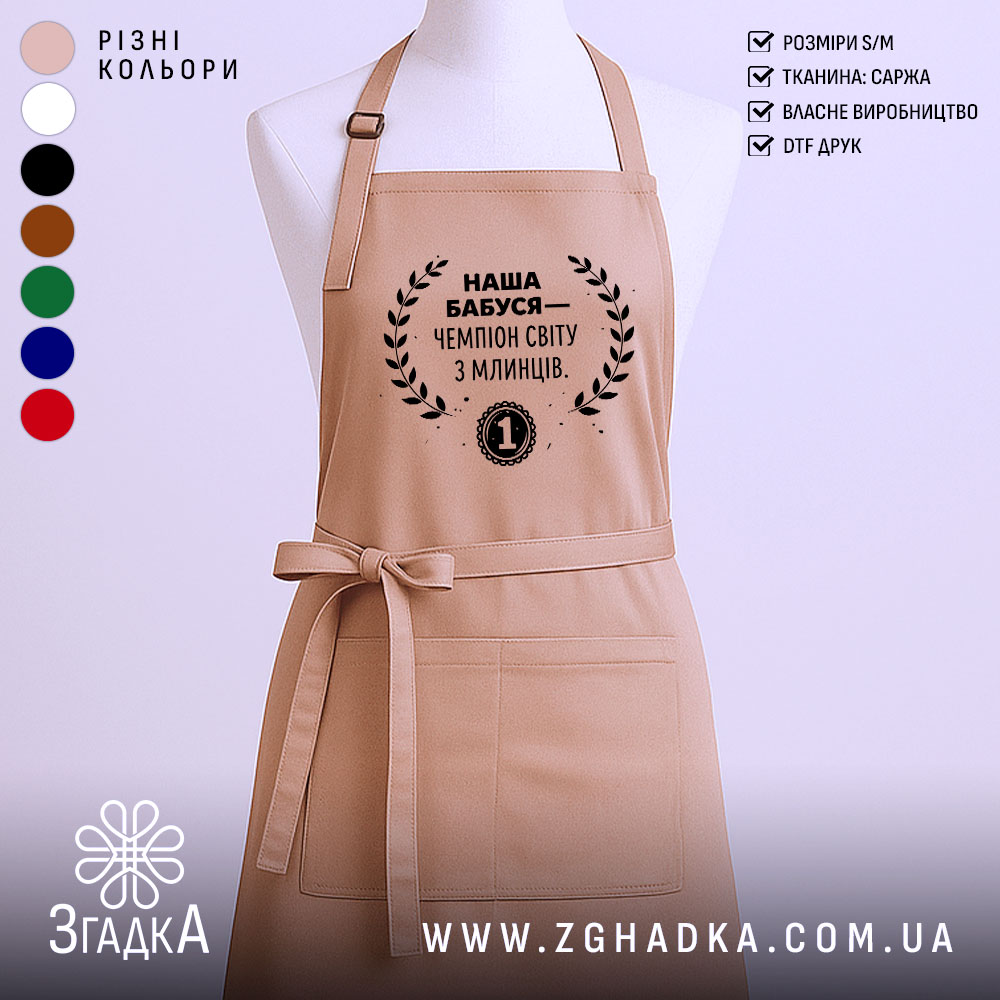 Фартух наша бабуся, бежевий колір, зображений на манекені з нейтральним фоном, принт чорного кольору з текстом і вінком.