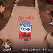 Фартух ось тобі й крінж у томаті, бежевий, на дерев'яному фоні, бренд.