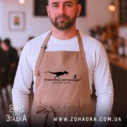 Фартух правильна мотивація, бежевий колір, на чоловікові, кафе на фоні, бренд Згадка.