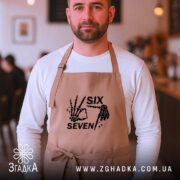 Фартух six seven мем дизайн, бежевий, на чоловікові, кафе на фоні, бренд.