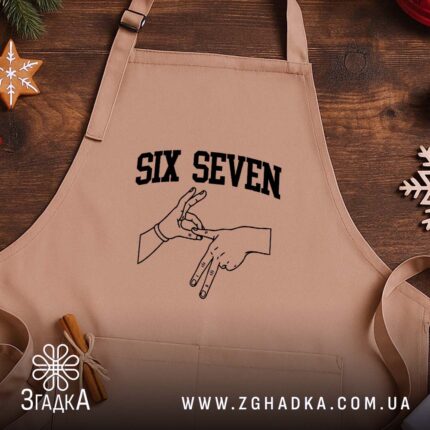 Фартух six seven жест руками, бежевий, на дерев'яному фоні, бренд Згадка.