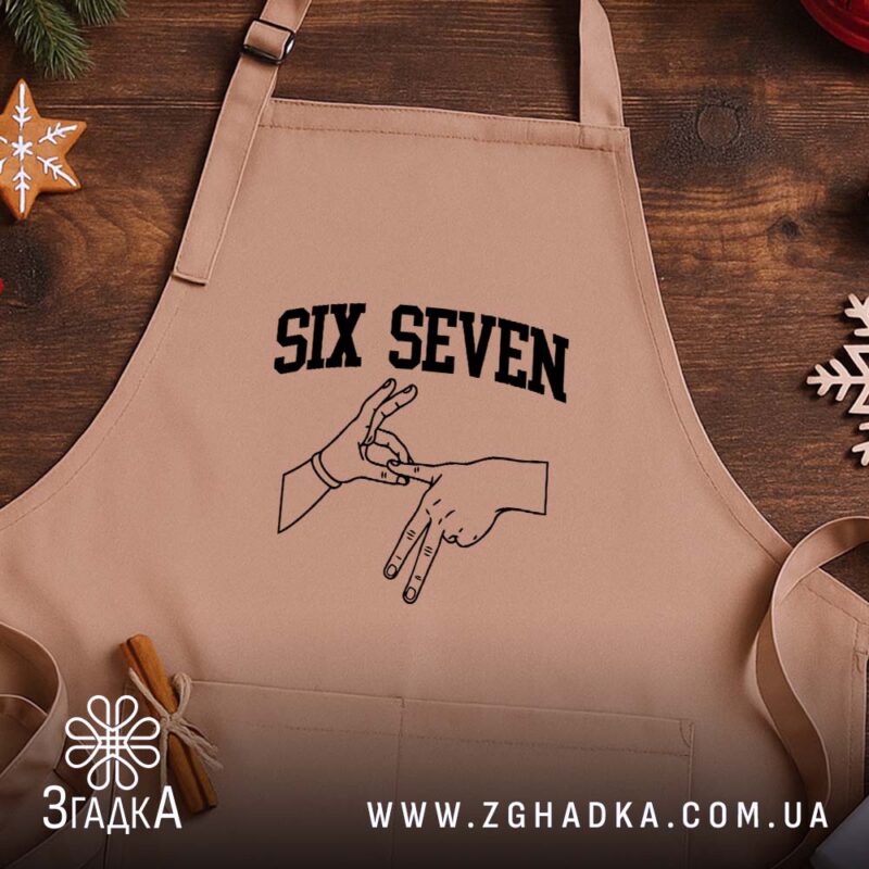 Фартух six seven жест руками, бежевий, на дерев'яному фоні, бренд Згадка.