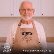 Фартух six seven жест руками, бежевий, на чоловікові, світлий фон, бренд Згадка.