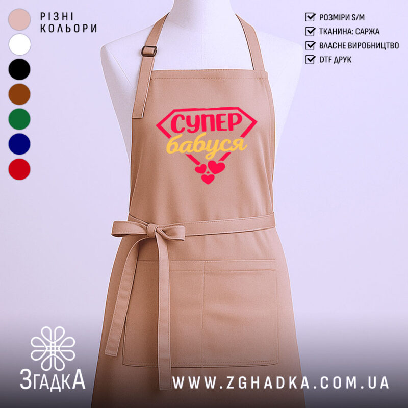 Фартух супер бабуся, бежевого кольору, з переднього ракурсу, на фоні світлого однотонного фону, з принтом у вигляді червоного діаманта з написом 'СУПЕР бабуся' жовтим кольором та червоними сердечками.