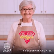 Фартух супер бабуся, бежевого кольору, з переднього ракурсу, на фоні світлого однотонного фону, з принтом у вигляді червоного діаманта з написом 'СУПЕР бабуся' жовтим кольором та червоними сердечками.
