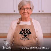 Фартух Тато може все, бежевий, на жінці з окулярами, світлий фон, бренд.