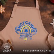 Фартух випускник кращої школи, бежевий, на дерев'яному фоні, бренд Згадка.