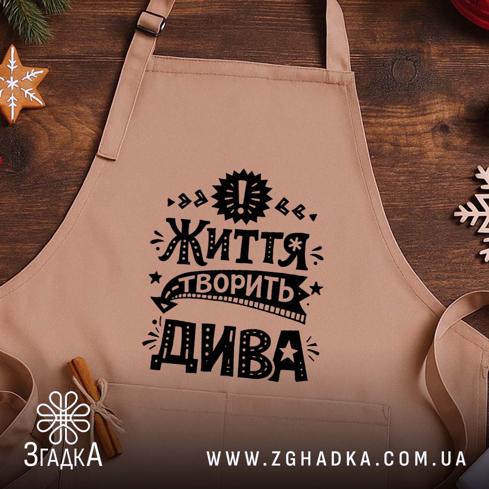 Фартух життя творить дива, бежевий, на дерев'яному фоні, бренд Згадка.