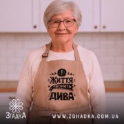 Фартух життя творить дива, бежевий, на жінці з окулярами, бренд Згадка.