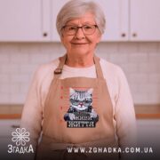 Фартух живи життя без системи, бежевий, на жінці, кухня на фоні, бренд.