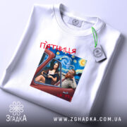 Футболка арт п’ятниця, біла, на столі, з принтом, що зображує двох персонажів у автомобілі на фоні зоряної ночі, текст 'п’ятниця' червоним шрифтом, етикетка на рукаві.