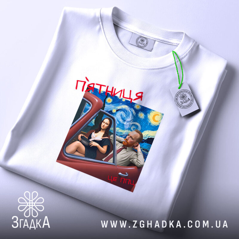 Футболка арт п’ятниця, біла, на столі, з принтом, що зображує двох персонажів у автомобілі на фоні зоряної ночі, текст 'п’ятниця' червоним шрифтом, етикетка на рукаві.