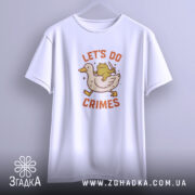 Футболка час для бешкету. Біла футболка, підвішена на вішалці, з принтом качки та жаби, що тримає ніж. Фон світло-фіолетовий, футболка виглядає об'ємно.