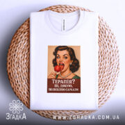 Футболка для любителів сарказму. Біла футболка, що лежить на плетеній основі, з принтом жінки з червоним льодяником. Фон білий, деталі принта яскраві, текст на ньому: 'Терапія? Ні, дякую, полюбляю сарказм'.