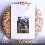 Футболка для робочих буднів. Біла футболка, складена на плетеній кошику, принт з групою тварин, текст: 'Мій внутрішній стан у понеділок вранці'. Фон світлий, акцент на текстурі кошика.