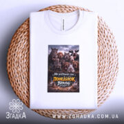 Футболка для роботи в понеділок, біла, складена на плетеній кошику, фон світлий, принт з зображенням тварин на темному фоні з текстом.