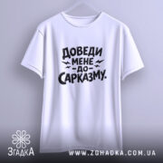 Футболка доведи мене до сарказму, біла, на вішалці, фон світло-сірий, принт чорного кольору з великим текстом.