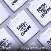 Футболка доведи мене до сарказму, біла, на моделі, з легким усмішкою, фон пастельного кольору, принт чорного кольору з великим текстом.