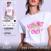 Футболка Good Vibes Only білого кольору, зображена на моделі, яка позує з легким усмішкою на фоні світлого однотонного фону. Принт на футболці містить малюнок двох сов з усмішками та написом 'Good Vibes Only' яскравого рожевого кольору, доповнений жовтими квітами.