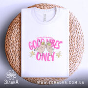 Футболка Good Vibes Only білого кольору, складена на плетеній кошику, з видимим принтом, що містить малюнок двох сов та напис 'Good Vibes Only' в рожевих кольорах. Кошик додає текстурний елемент до зображення.