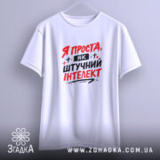 Футболка я як штучний інтелект, біла, зображена на вішалці, фон світло-сірий, принт червоними і чорними літерами з написом 'Я ПРОСТА, ЯК ШТУЧНИЙ ІНТЕЛЕКТ'.