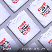 Футболка я як штучний інтелект, біла, зображена на моделі з коротким рукавом, фон світло-фіолетовий, принт червоними і чорними літерами з написом 'Я ПРОСТА, ЯК ШТУЧНИЙ ІНТЕЛЕКТ'.