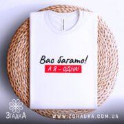 Футболка я одна, білого кольору, складена на плетеній основі, фон світло-сірий, принт чорного кольору з червоним фоном, текст "Вас багато! А я – одна!".